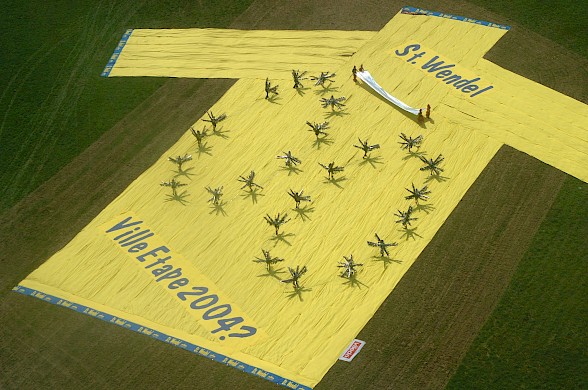 (Foto: 2002 siegte die Stadt St. Wendel souverän. Mit einer fulminanten Inszenierung an der Rennstrecke und dem größten gelben Trikot der Welt erzielte sie den 1. Platz des offiziell ausgeschriebenen Dekorationswettbewerbs aller Etappenorte.